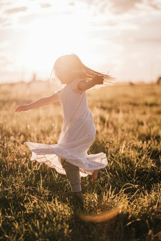 DAY 14 - GOOD FOR EVIL A young girl twirls joyfully in a sunlit field during a summer sunset.
