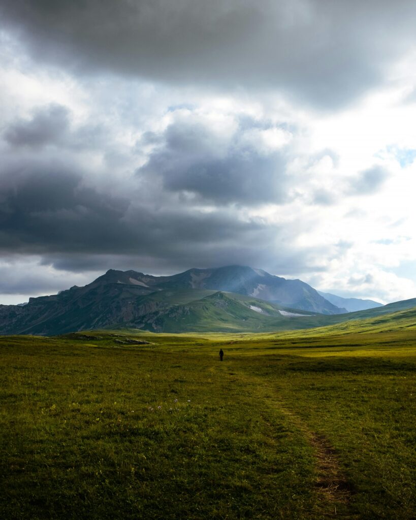 DAY 59 – WALK THE TALK Expansive view of Adygea's mountainous landscape under a dramatic cloudy sky, ideal for nature lovers.