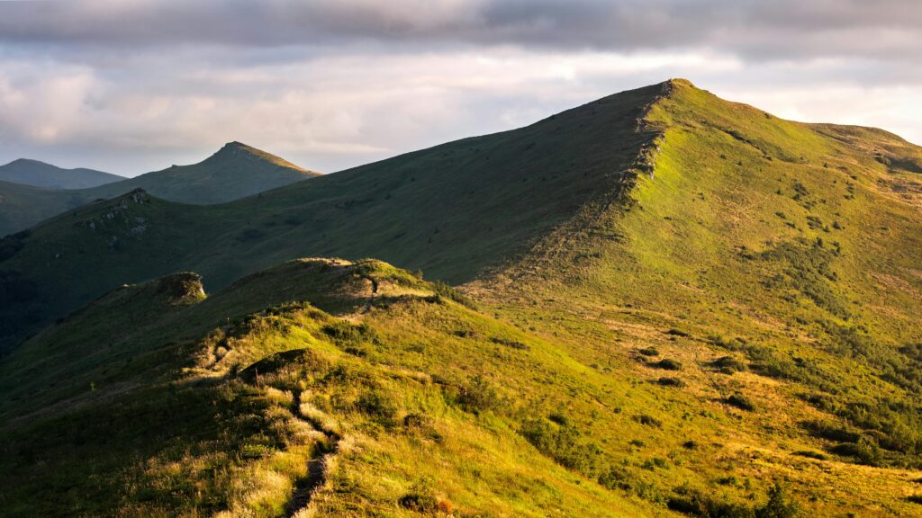 DAY 50 - IN THE NAME OF THE LORD OF HEAVEN’S ARMIES Bieszczady mountain range with green valleys and trails in early morning light, perfect for hiking adventures.