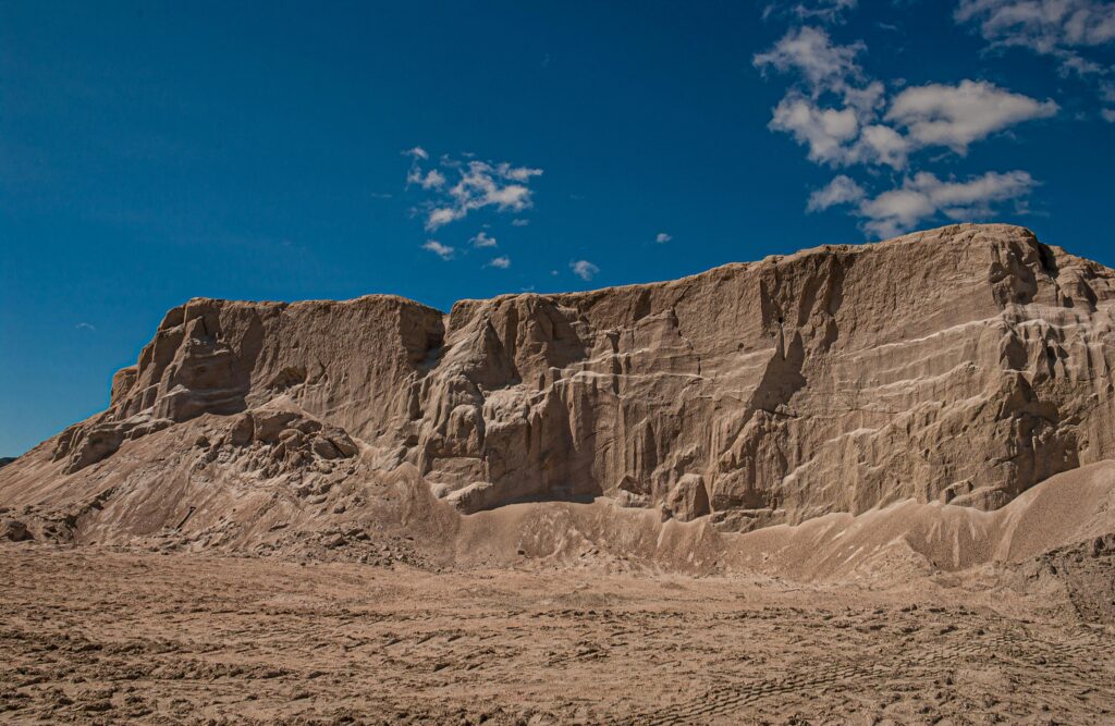 A striking desert cliff with unique erosion patterns under a vibrant blue sky.