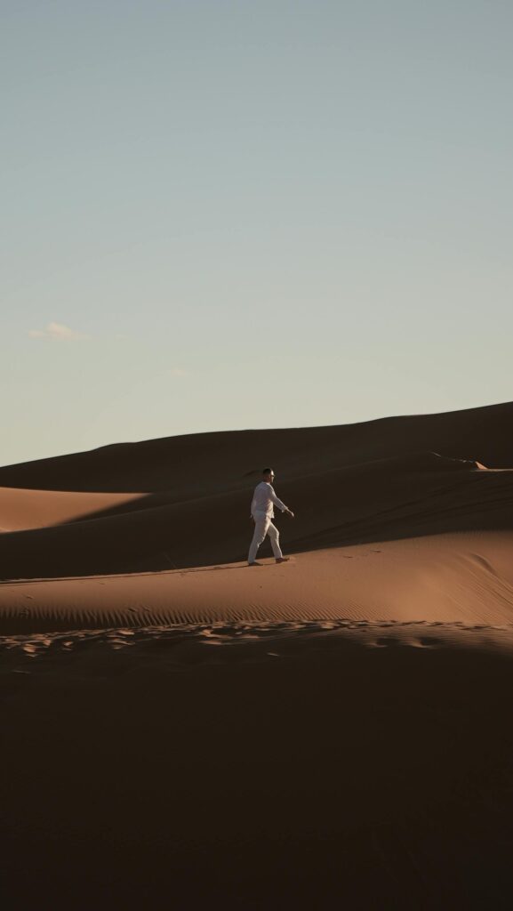 DAY 57 - THE UNSUNG HERO A lone person traverses the vast dunes of the Merzouga Desert in Morocco.