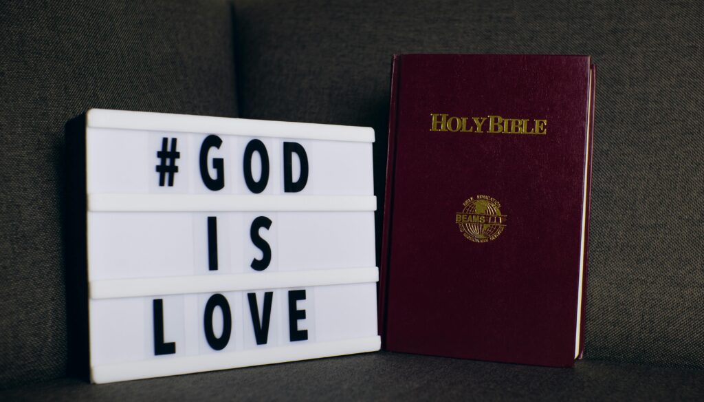 DAY 45 - GOD- greatest love of our lives Holy Bible next to a lightbox displaying '#God is Love' message on a sofa.