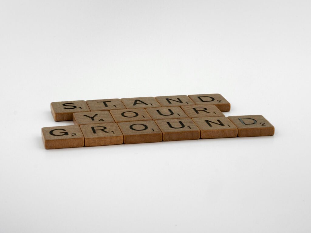 DAY 36 - STAND YOUR GROUND Scrabble tiles display the empowering phrase 'Stand Your Ground' on a white surface.