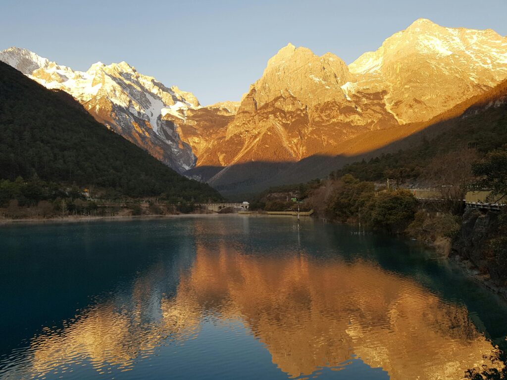 Breathtaking view of Jade Dragon Snow Mountain reflecting in a lake during sunset in Lijiang, China.