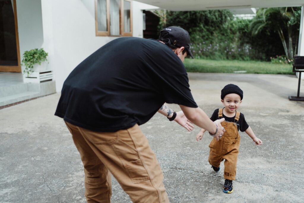 Joyful father and son bonding while playing outside their home. Capturing family happiness.