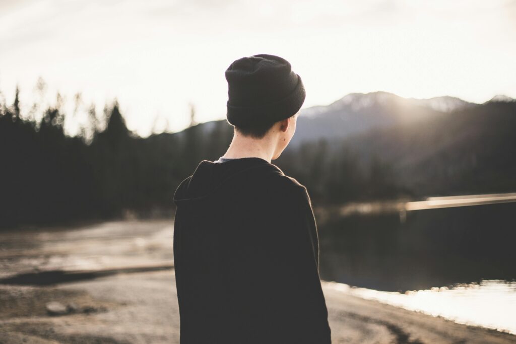 A person gazes at the tranquil lake during sunset, embodying serenity and solitude.