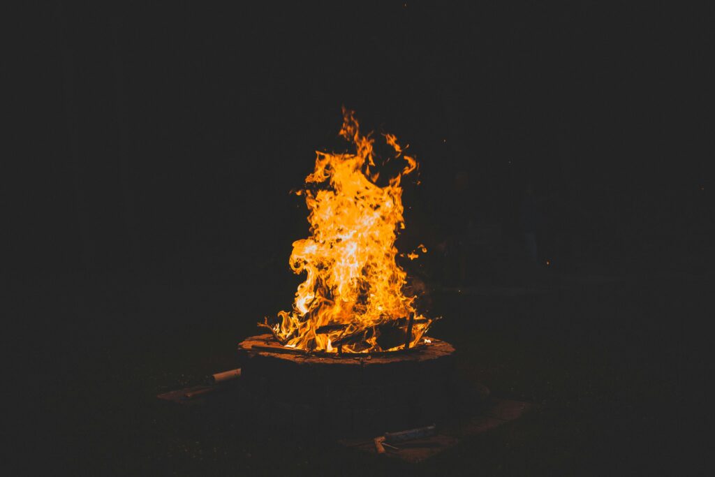 A lively campfire casting warm flames on a dark starry night, perfect outdoors.