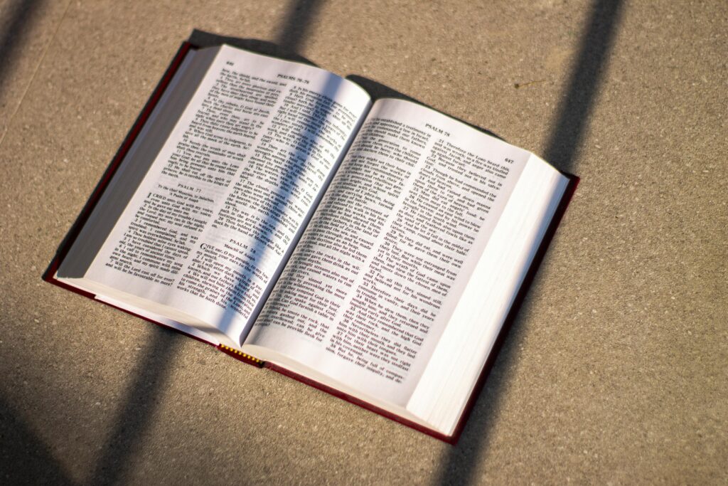 An open Bible casting shadows on a floor in natural light, emphasizing scripture and reflection.
