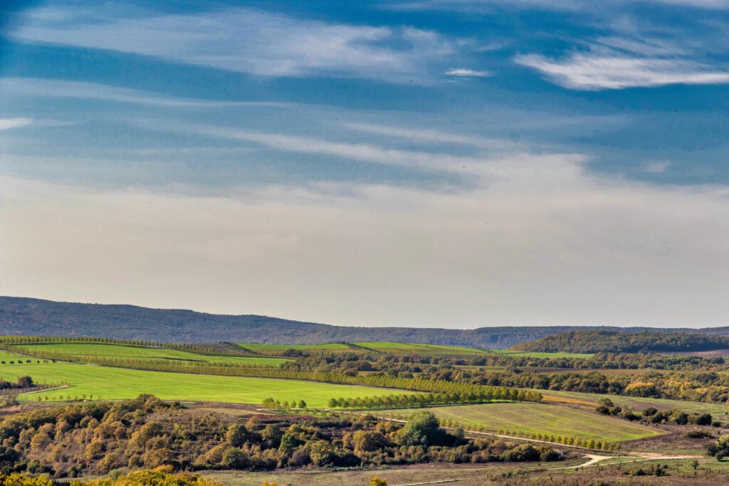 Beautiful view of rolling hills and vibrant green fields under a bright blue sky.