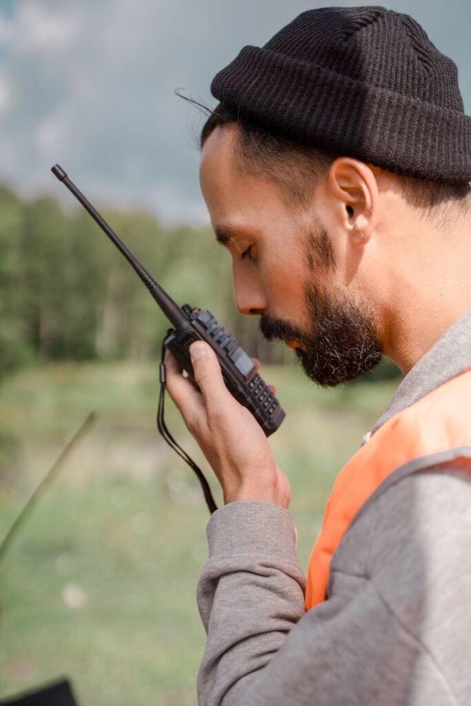 Male volunteer in outdoors using a walkie-talkie for search and rescue coordination.
