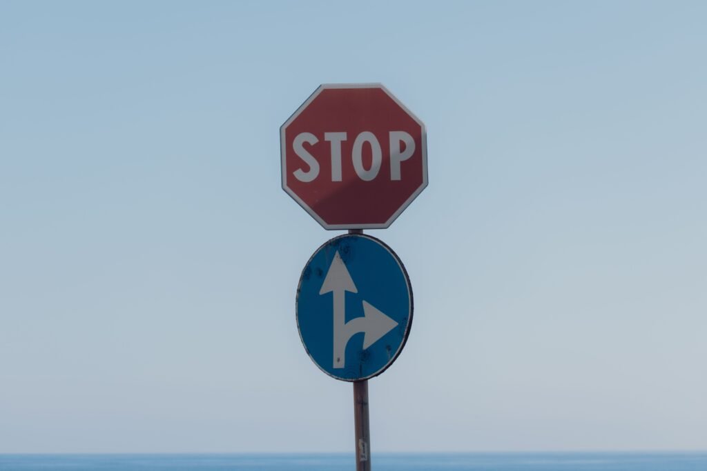 Stop sign with directional arrows at Lido di Noto, Sicily with sky backdrop.