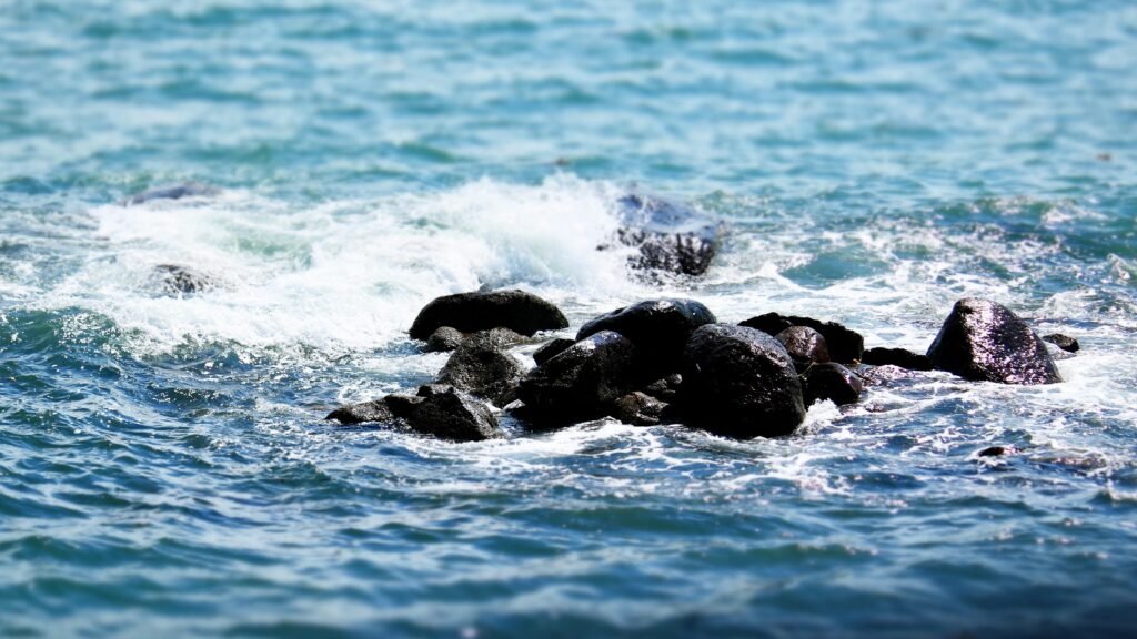 Waves crashing on a rocky shoreline with vibrant blue ocean in Vietnam.