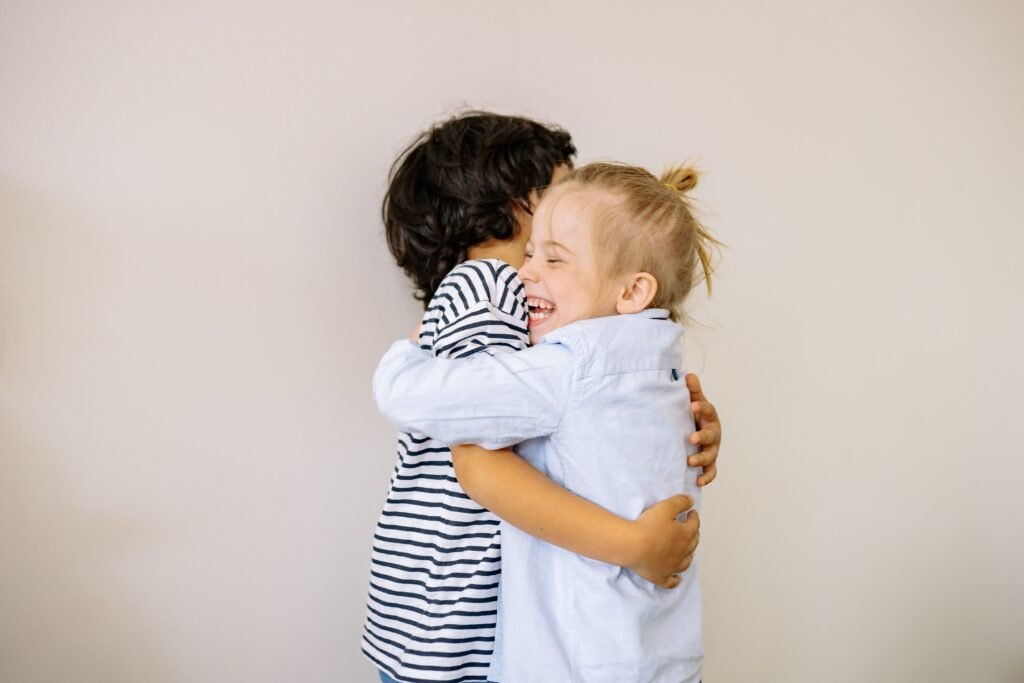 Two happy children sharing a heartfelt hug indoors, showcasing innocence and love.