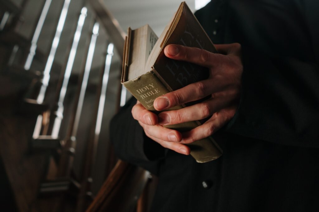Close-up view of adult hands holding a Holy Bible on a staircase, symbolizing faith and spirituality.