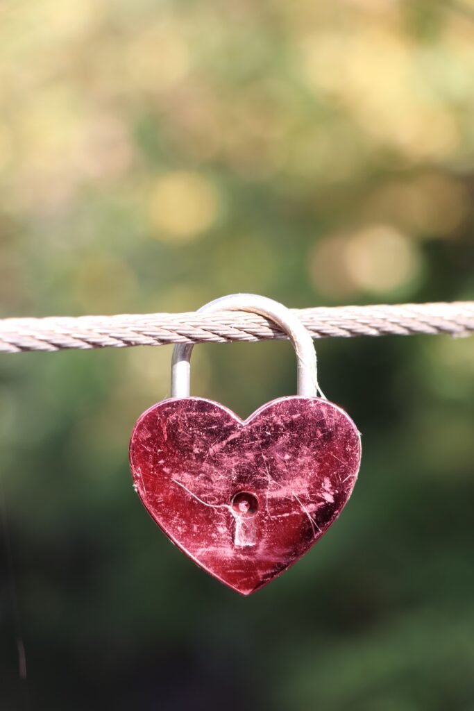 A red heart-shaped padlock hanging on a cable, symbolizing love and commitment.