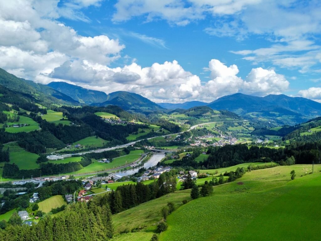 Breathtaking aerial shot of lush green valleys and mountains in the Austrian Alps.