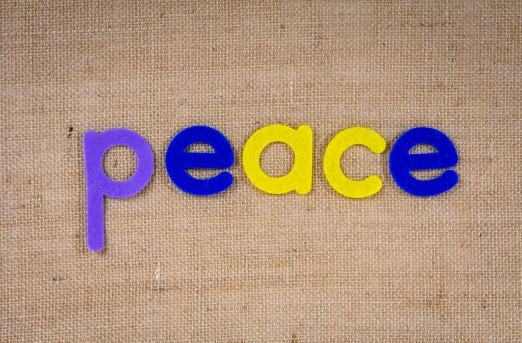 Vibrant letters spelling 'peace' on textured burlap surface.