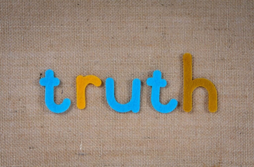 The word 'truth' in colorful felt letters on a burlap background.