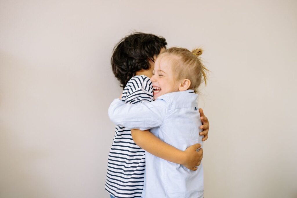 Two happy children sharing a heartfelt hug indoors, showcasing innocence and love.