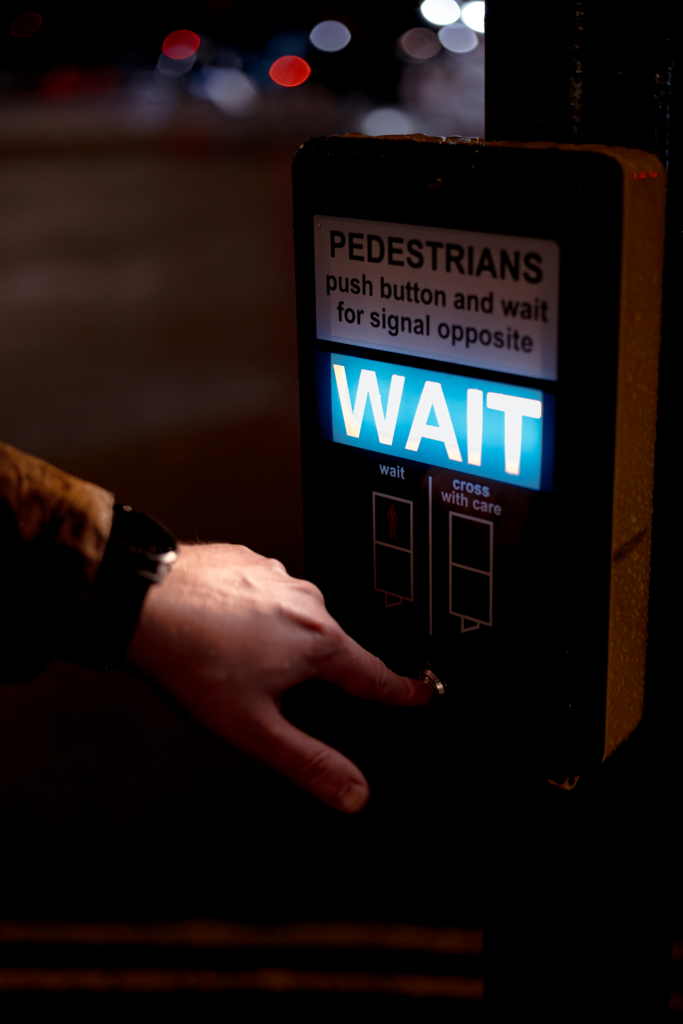 25 SEPTEMBER 2026, DAY 268 - JUST WAIT! Close-up of a hand pressing a crosswalk button at night in London, England.