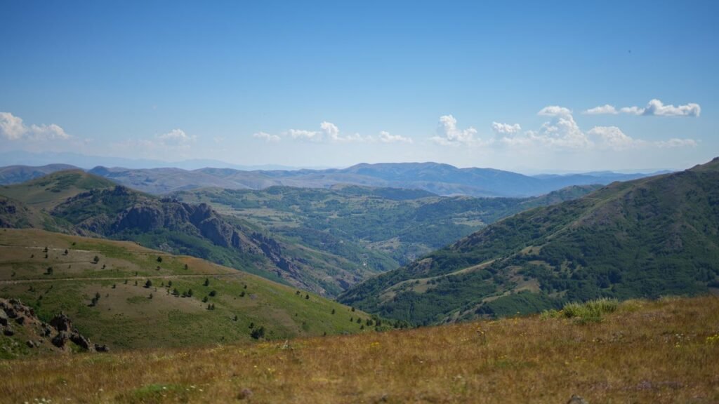 Expansive view of verdant mountain landscape under a bright blue sky.