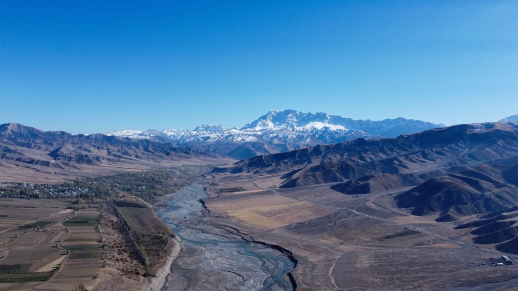 29 SEPTEMBER 2026, DAY 272 - I HAVE CHOSEN THEE Drone view of Osh Region's rugged terrain with snow-capped mountains and dry riverbed.
