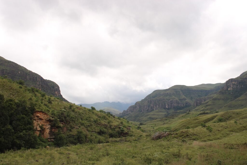 Majestic Drakensberg mountain landscape under a cloudy sky, showcasing lush greenery.
