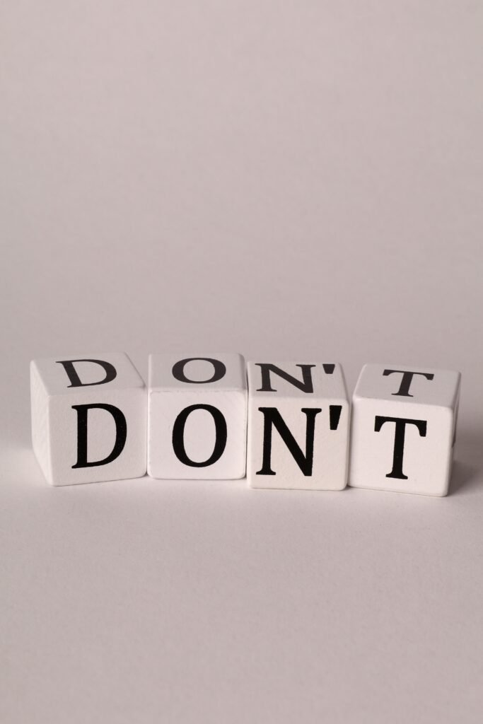 Four white dice with black letters spelling 'DON'T' against a neutral background.
