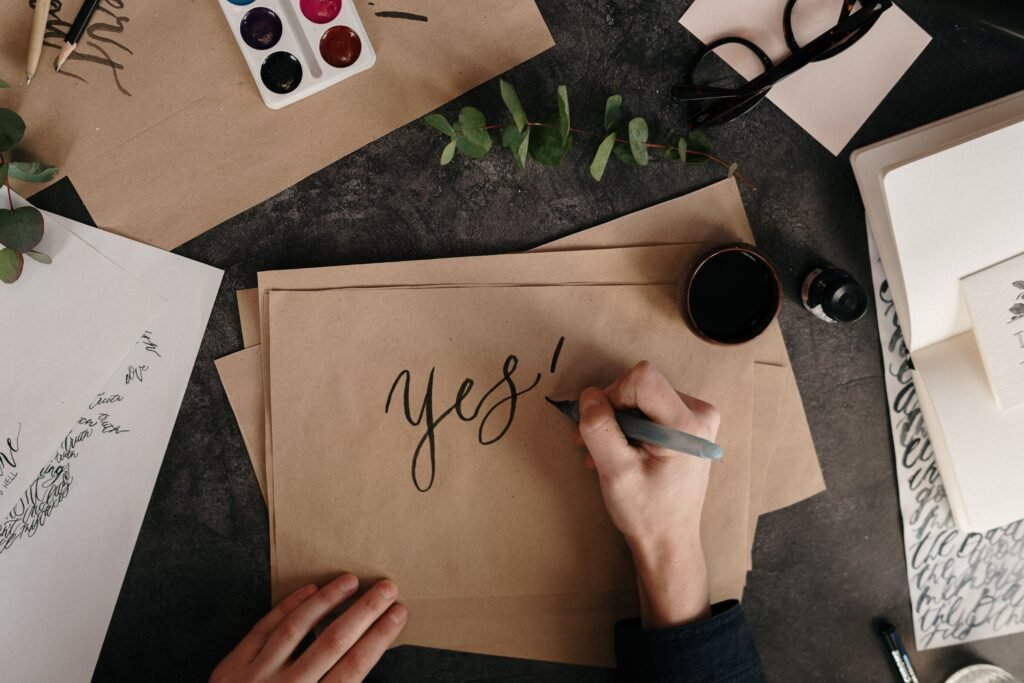 Artistic calligraphy session featuring the word 'yes!' with natural eucalyptus accents.