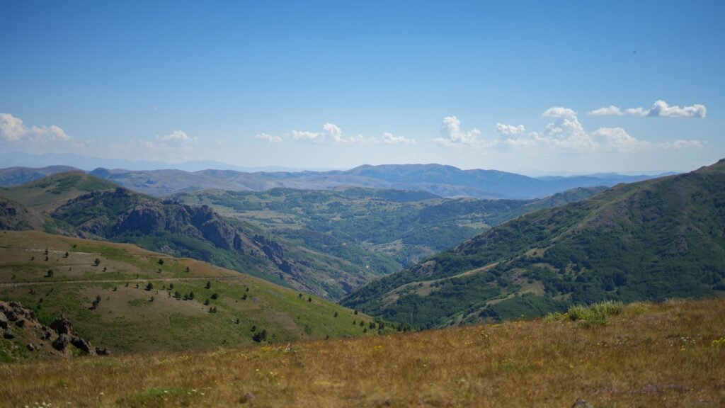 Expansive view of verdant mountain landscape under a bright blue sky.